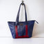 Wearsos blue and red tote bag hanging up on a well.