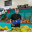 A young man holding his pineapple-leather, sustainable gym bag at a fruit store.