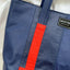 Close shot of an upcycled blue tote bag showing red details and the Wearsos brand tag.